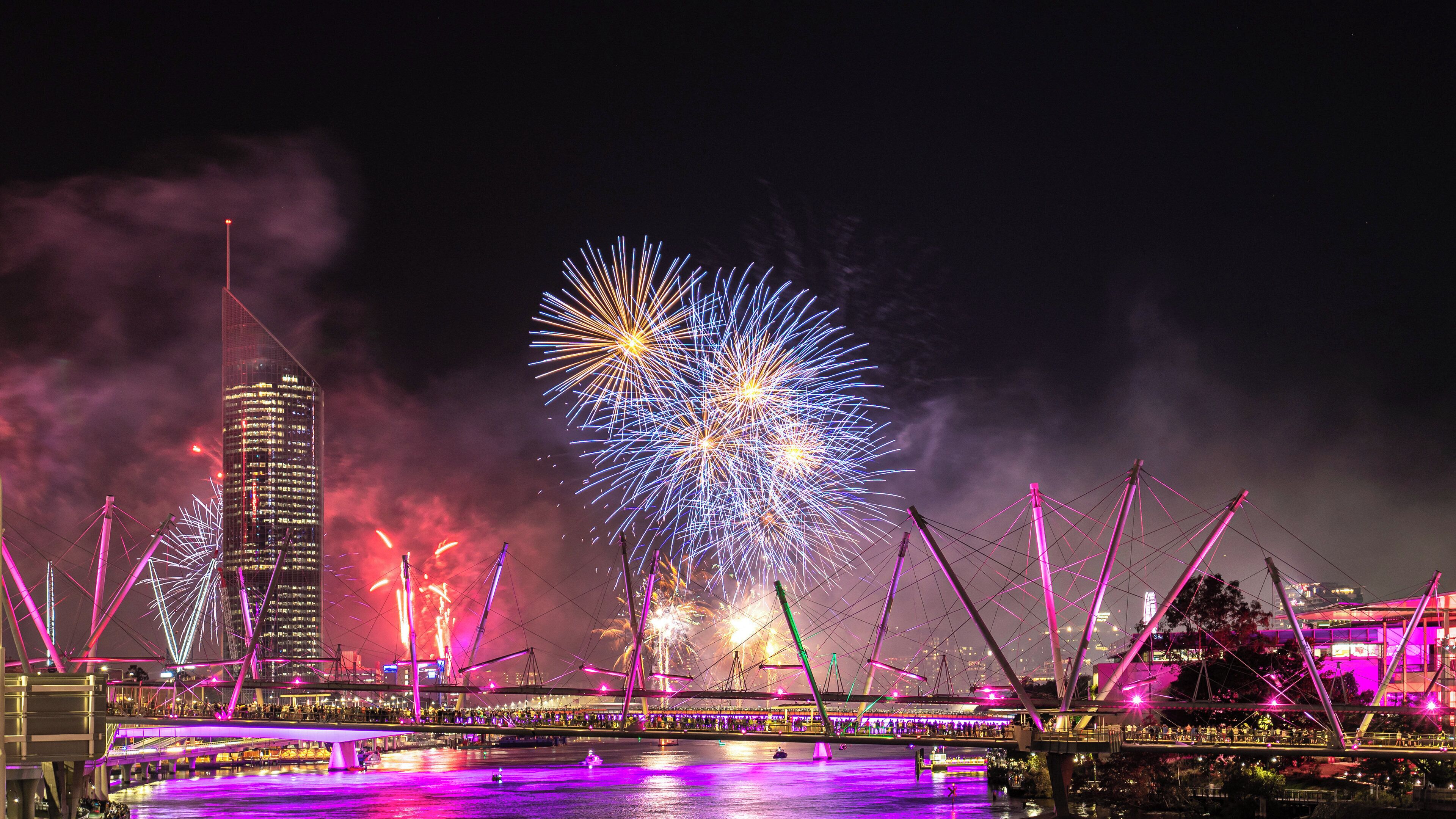 Une vue nocturne d’une ville, avec un pont et un feu d’artifice.