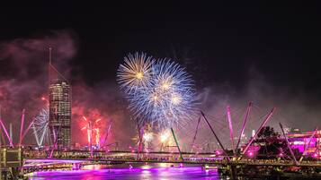 Un paisaje urbano nocturno con un puente y un espectáculo de fuegos artificiales.