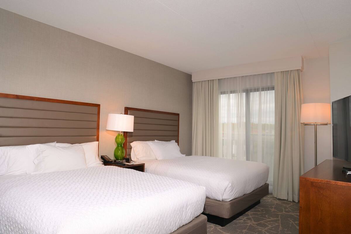 Ein Hotelzimmer mit zwei Betten, einem Schreibtisch und einem Fernseher.
