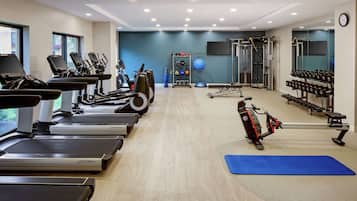 Ein Fitnessstudio mit Laufbändern, Crosstrainern, Krafttrainingsgeräten und Kurzhanteln.