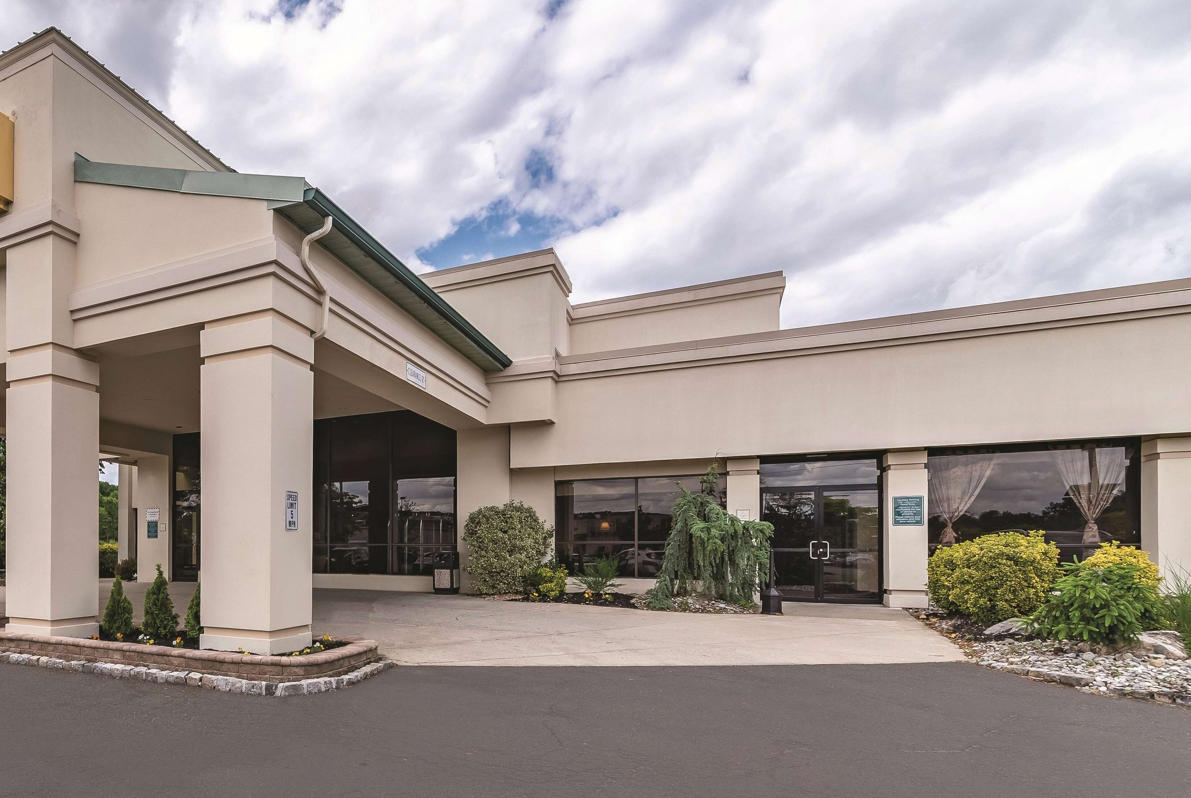 A building with a covered entrance, large windows, and a landscaped area with plants and shrubs.