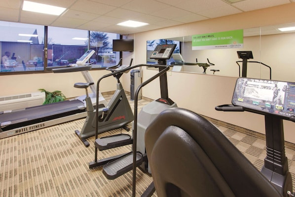 Un gimnasio de hotel con cintas de correr, una bicicleta estática y una máquina de remo.