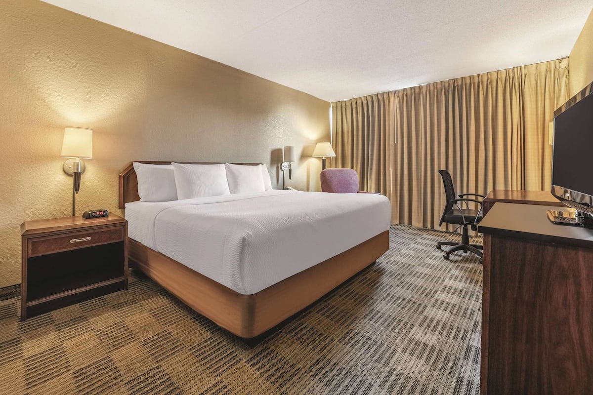 Habitación de hotel con una cama grande, un escritorio, una silla y dos lámparas.