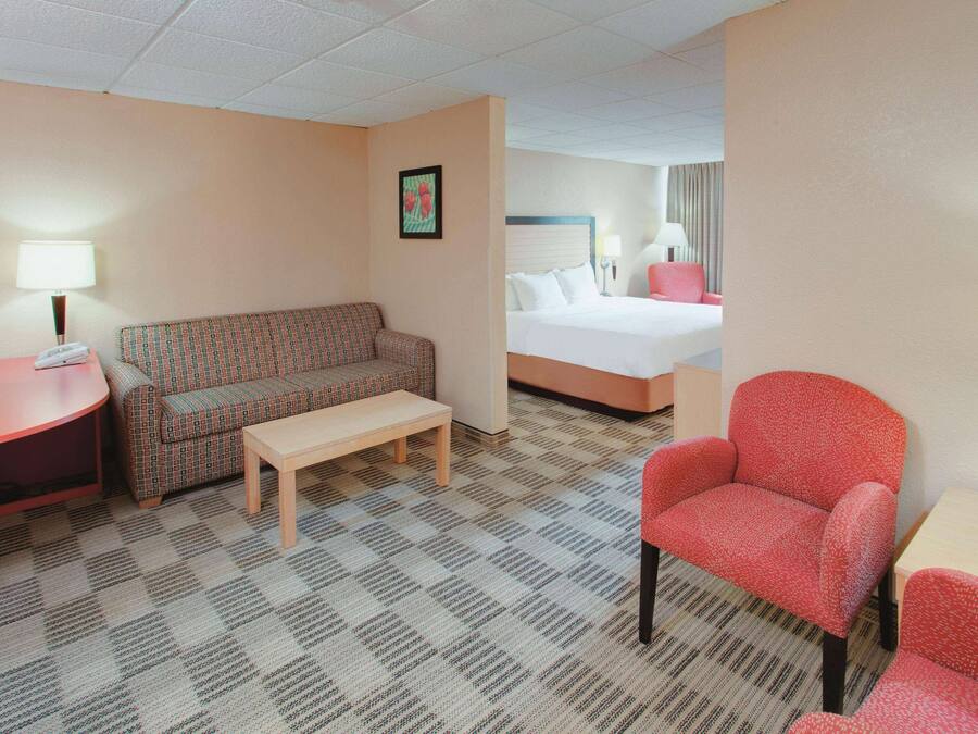 Una habitación de hotel con cama, sofá, sillón, mesa y lámpara.