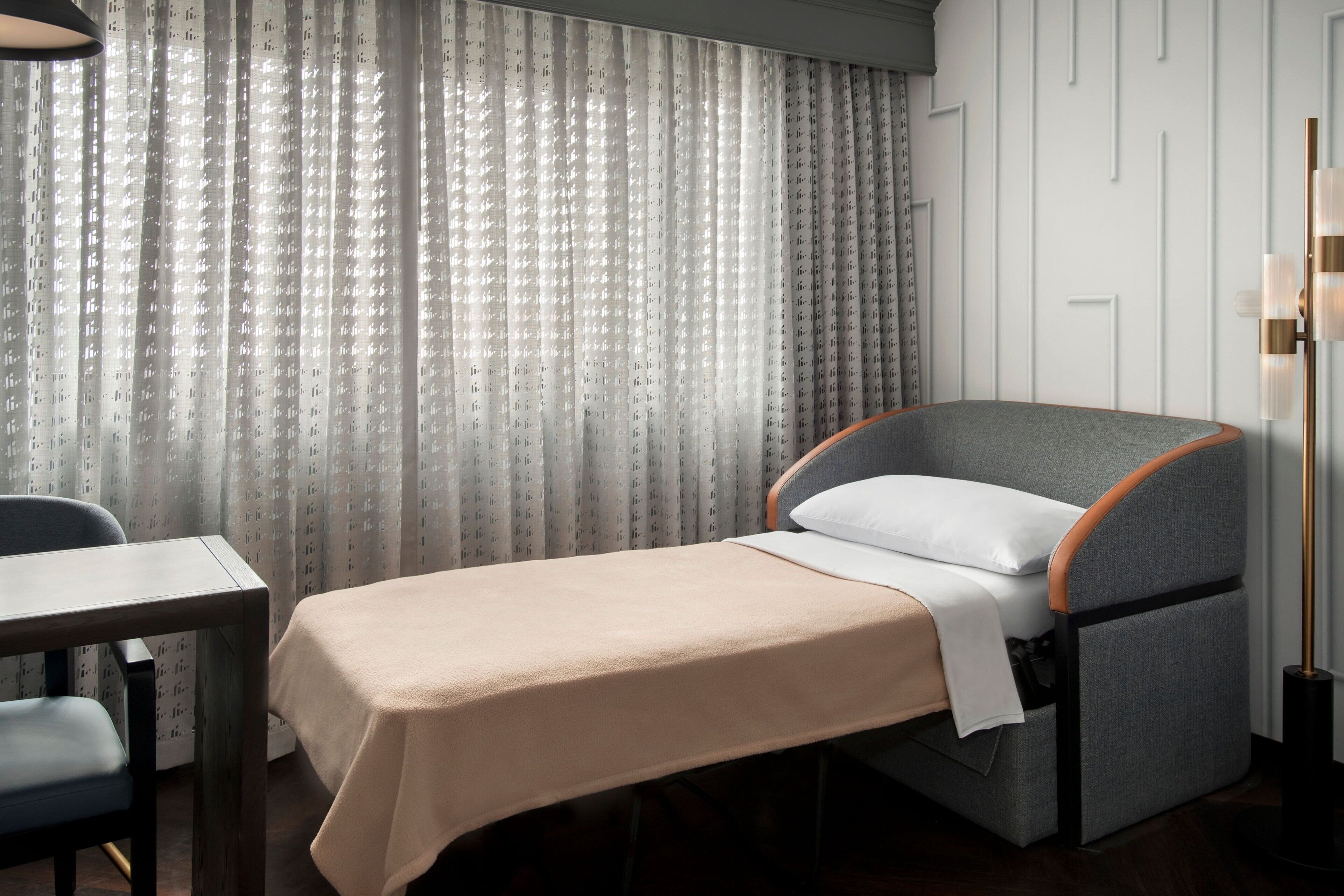Una habitación pequeña con una cama, una mesita y una silla.