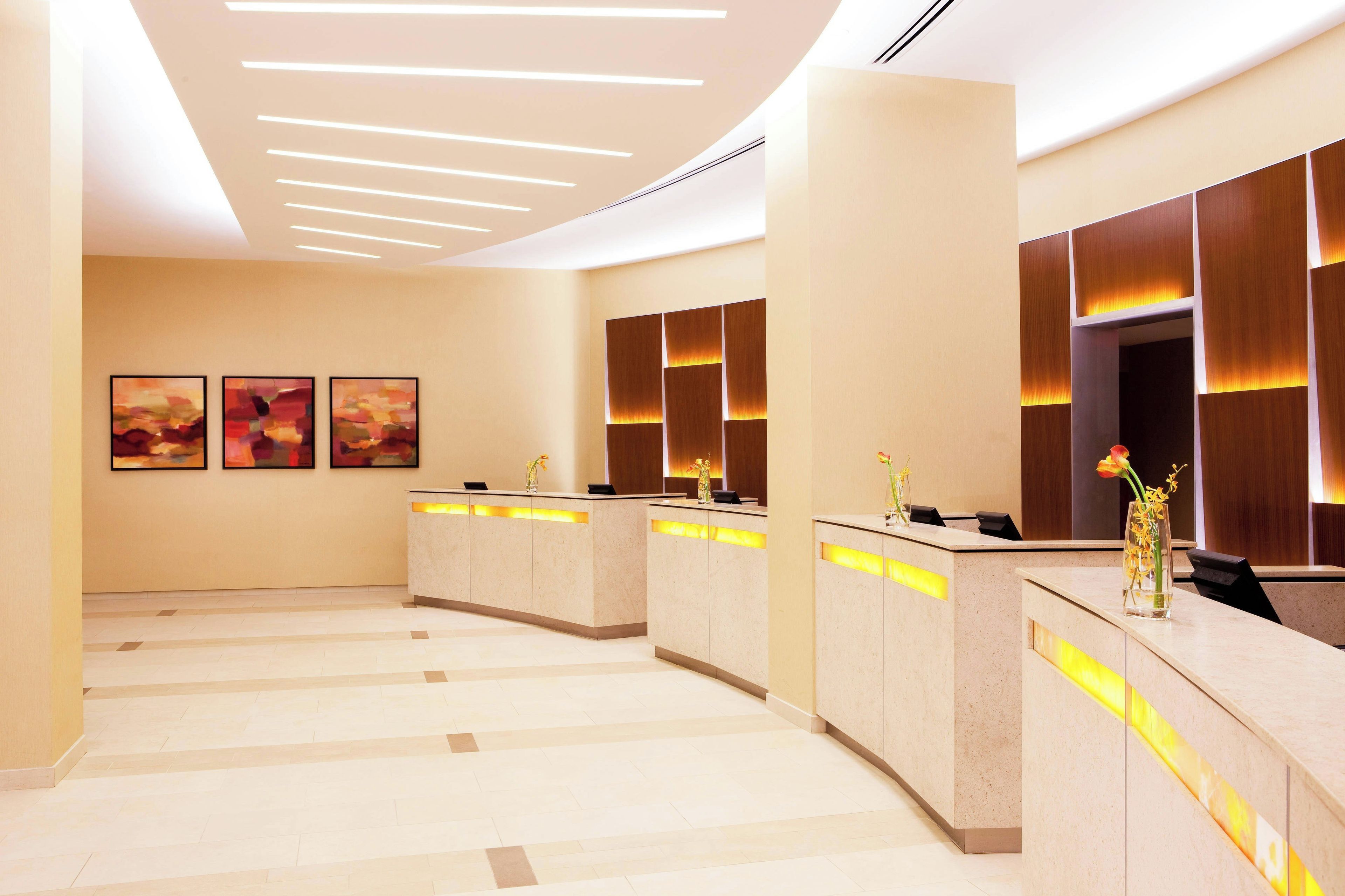 A reception area with a modern design, featuring a reception desk, wall-mounted artwork, and a tiled floor.