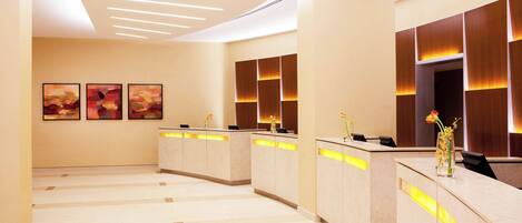 A reception area with a modern design, featuring a reception desk, wall-mounted artwork, and a tiled floor.