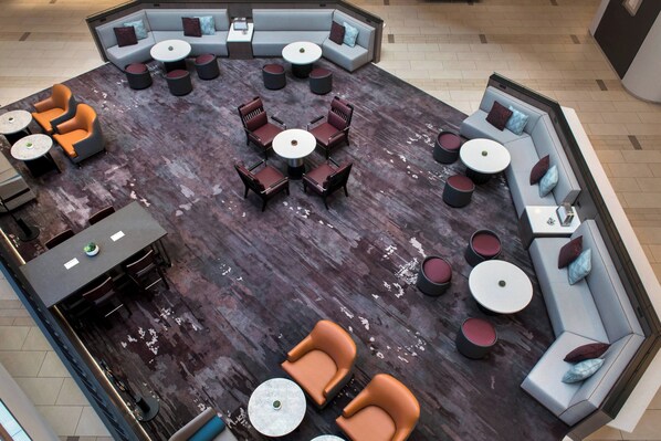 A spacious lounge area with multiple seating arrangements, including sofas, chairs, and round tables.