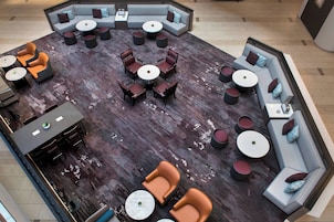 Een ruime lounge met verschillende zithoeken, waaronder banken, fauteuils en ronde tafels.