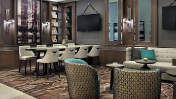 Een moderne hotel lobby met een eetgedeelte, zitplaatsen, een flatscreen televisie en een groot raam met uitzicht op de stad.