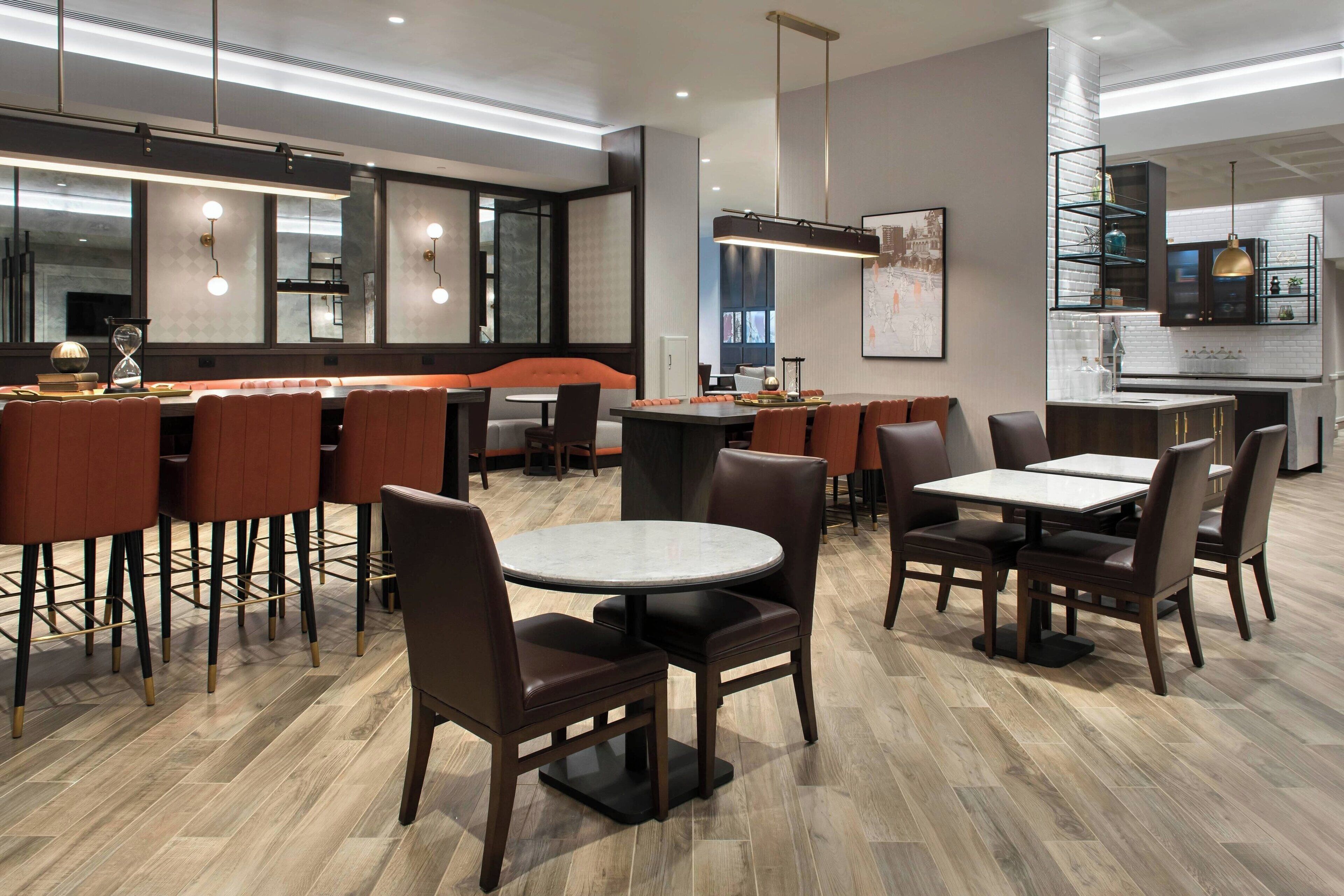 Ein modernes Restaurant mit runden Tischen, hohen Barhocker und einem sichtbaren Küchenbereich.