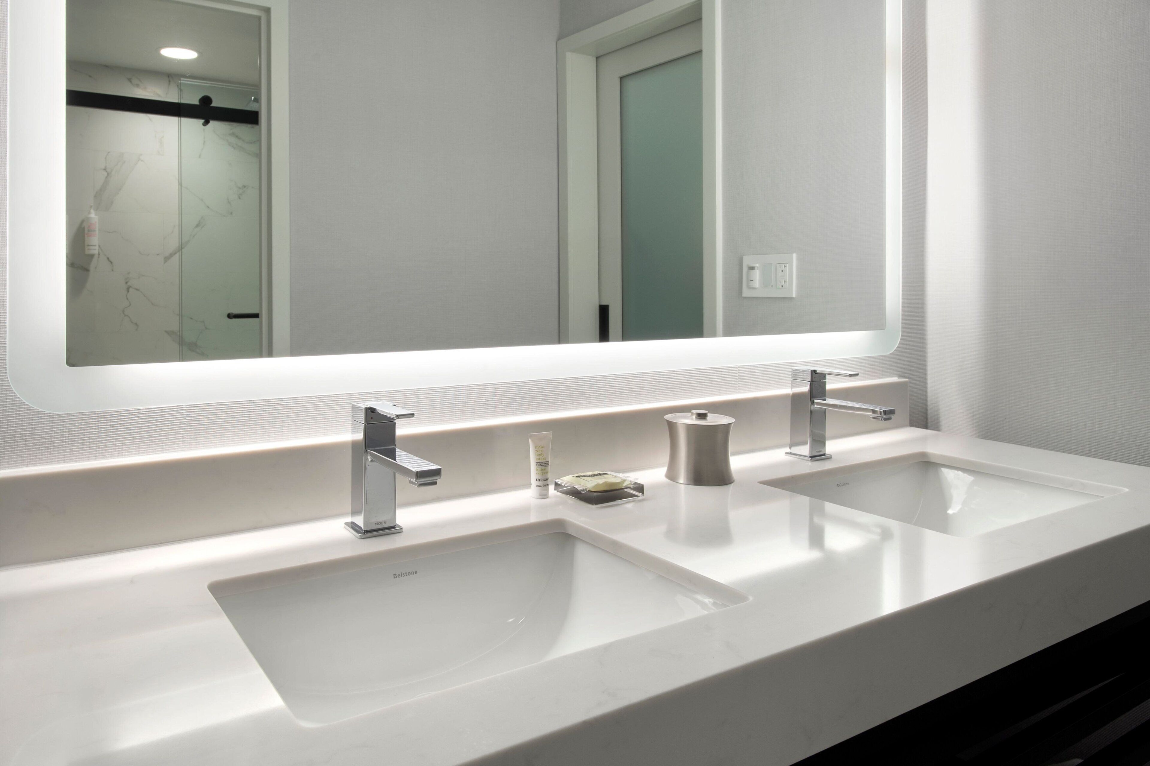 A modern bathroom with two sinks, a large mirror, and a shower area.