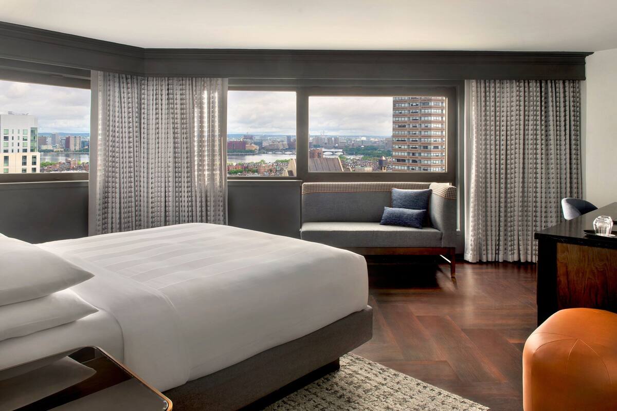 A hotel room with a large bed, a sofa, a desk, and a view of the city.