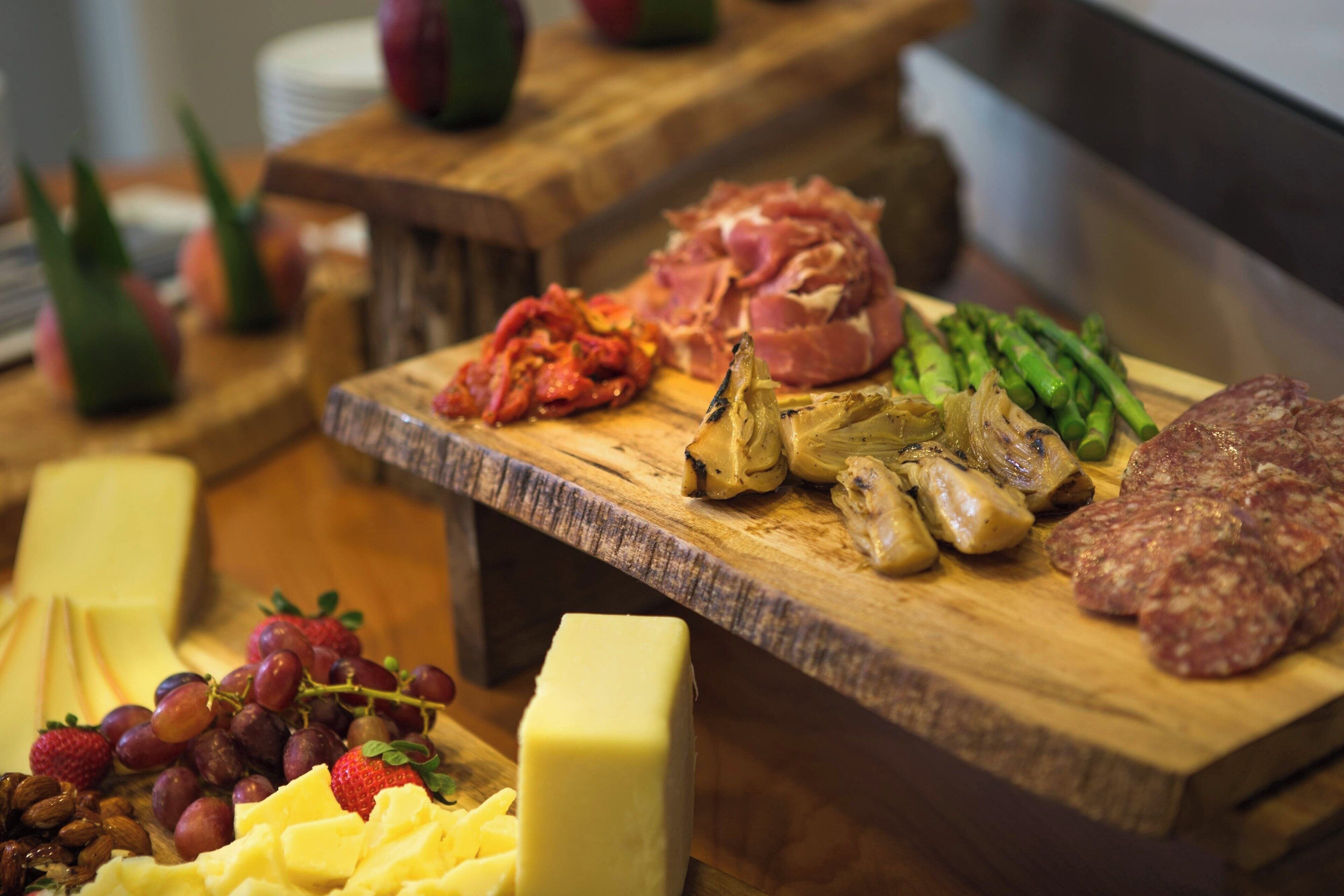 Un tagliere con diversi cibi tra cui formaggio, uva e salumi.