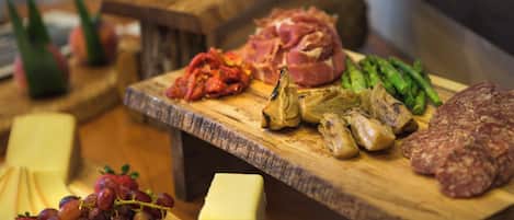 A wooden board with various food items including cheese, grapes, and meat.