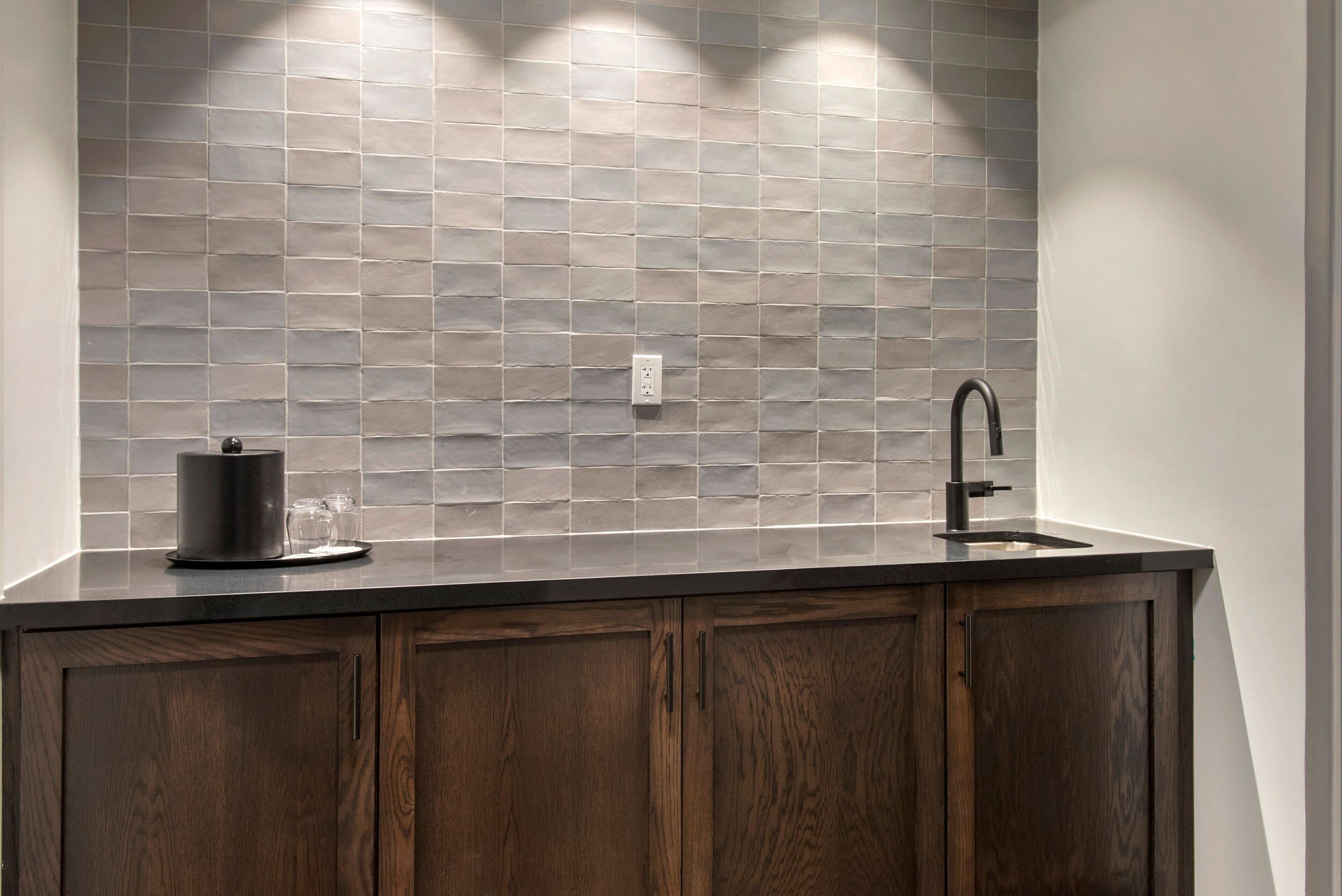 A kitchen with a dark wooden cabinet, a modern faucet, and a tiled backsplash.