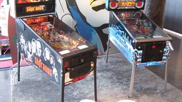 Enjoy classic pinball action with 'The Sopranos' themed machines, featuring clear glass fronts and comfortable seating for players.