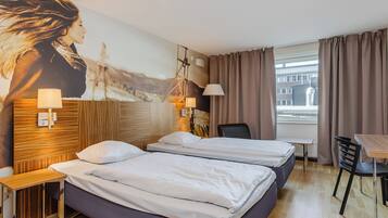 Una habitación de hotel con dos camas, un escritorio, una silla, una lámpara y un cuadro grande en la pared.