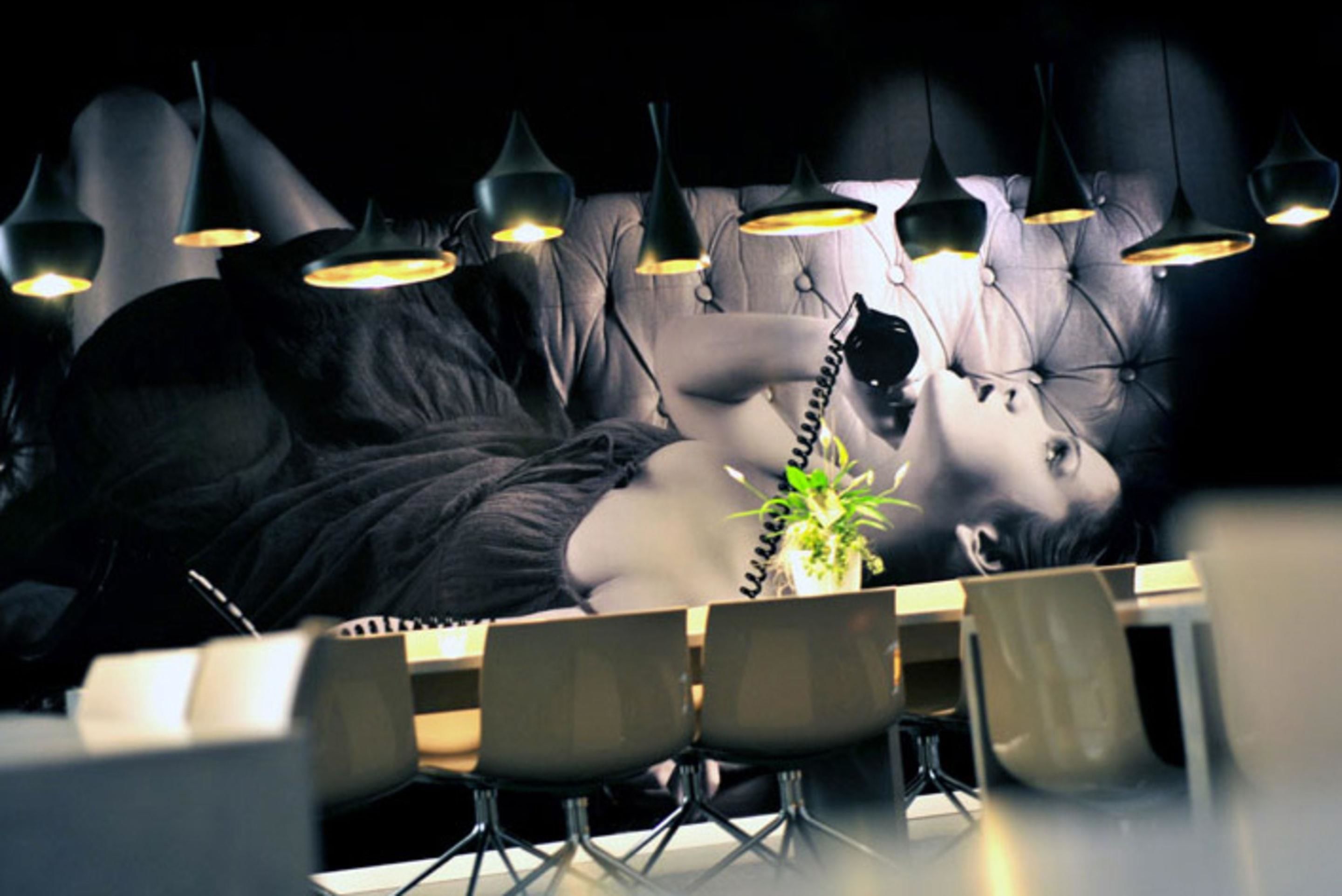 A room with a tufted leather sofa, a small potted plant, and multiple pendant lights.