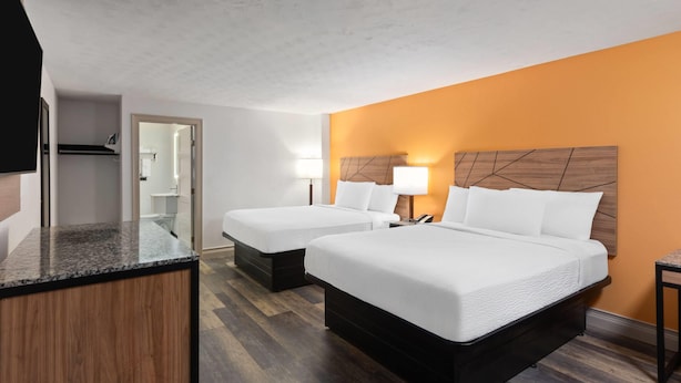 A hotel room with two beds, a wooden headboard, a desk, and a mirror. - Howard Johnson by Wyndham Malden Boston Area (Malden)
