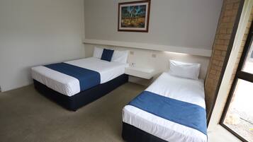 A hotel room with two single beds, a nightstand, a painting on the wall, and a window with a view.