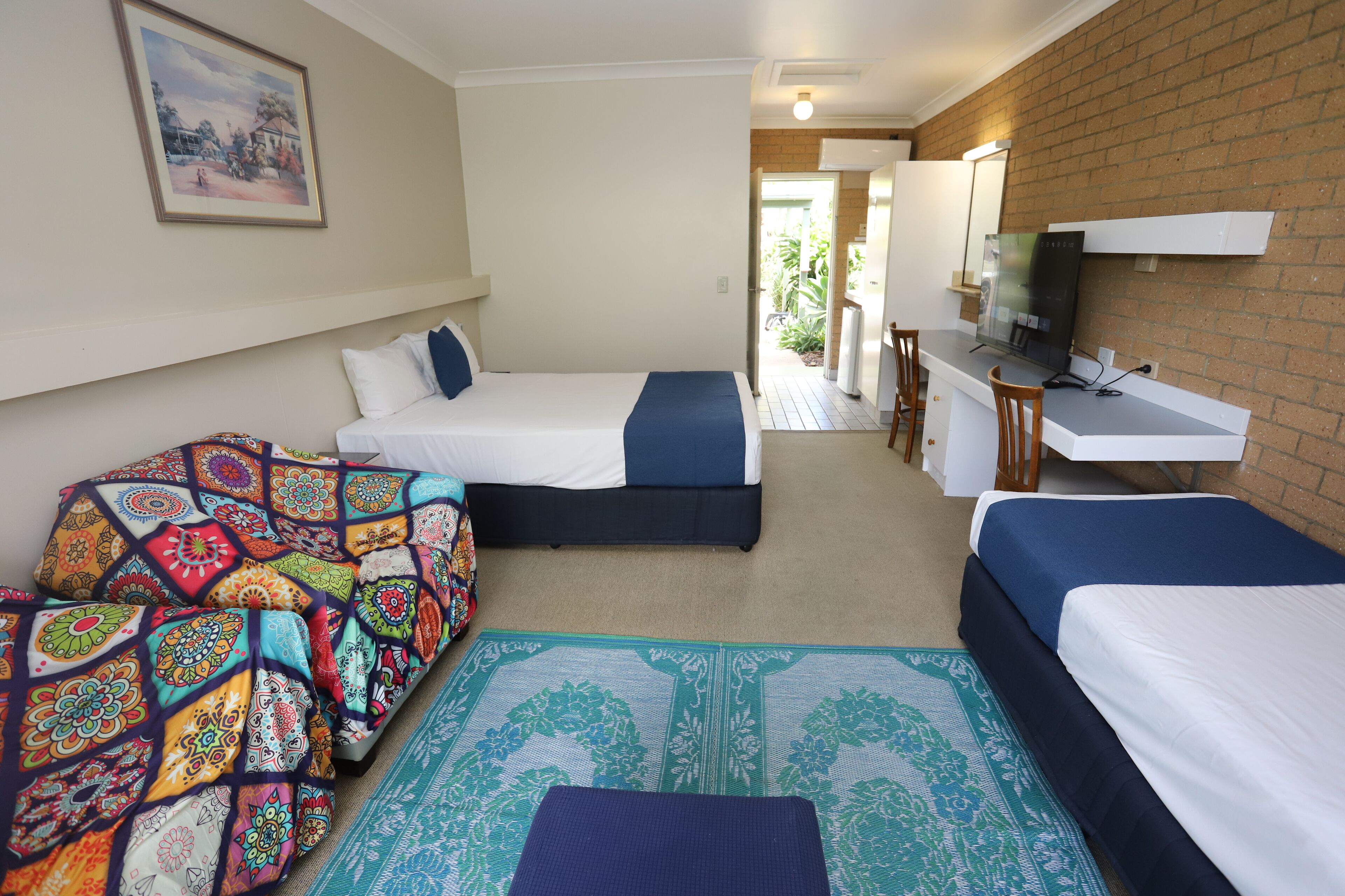 A hotel room with two beds, a desk, and a TV.