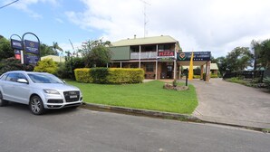 A motel with a signboard, a pizza restaurant, and a car parked in front. - Great Eastern Motor Inn (Monkland)