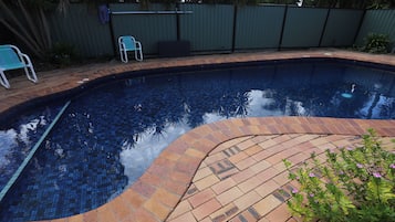 Una piscina al aire libre, sillones reclinables de piscina