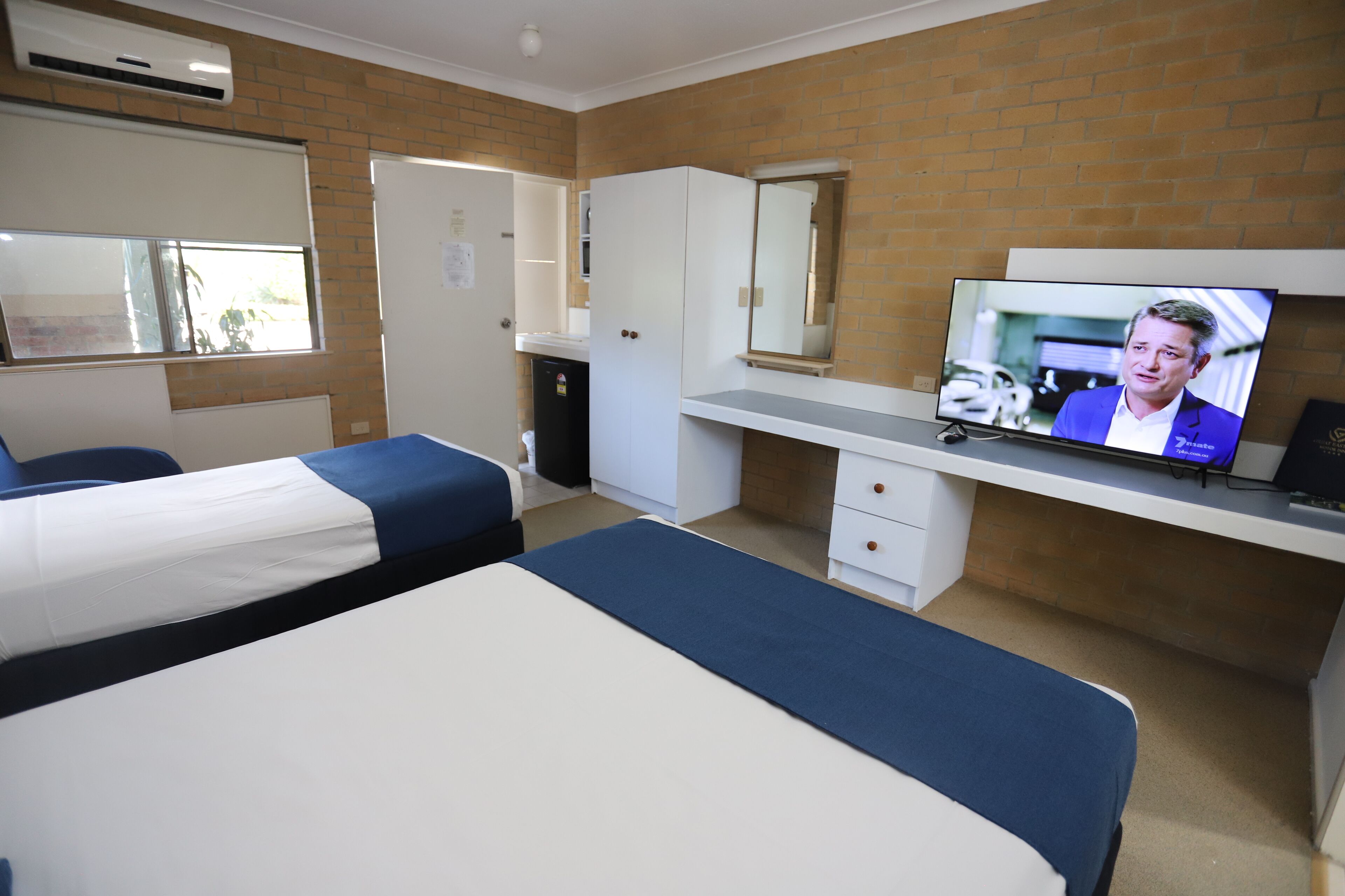 Ett hotellrum med två sängar, en tv, ett skrivbord och en spegel.
