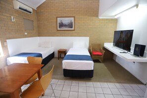 A hotel room with two beds, a TV, a desk, and a small table.