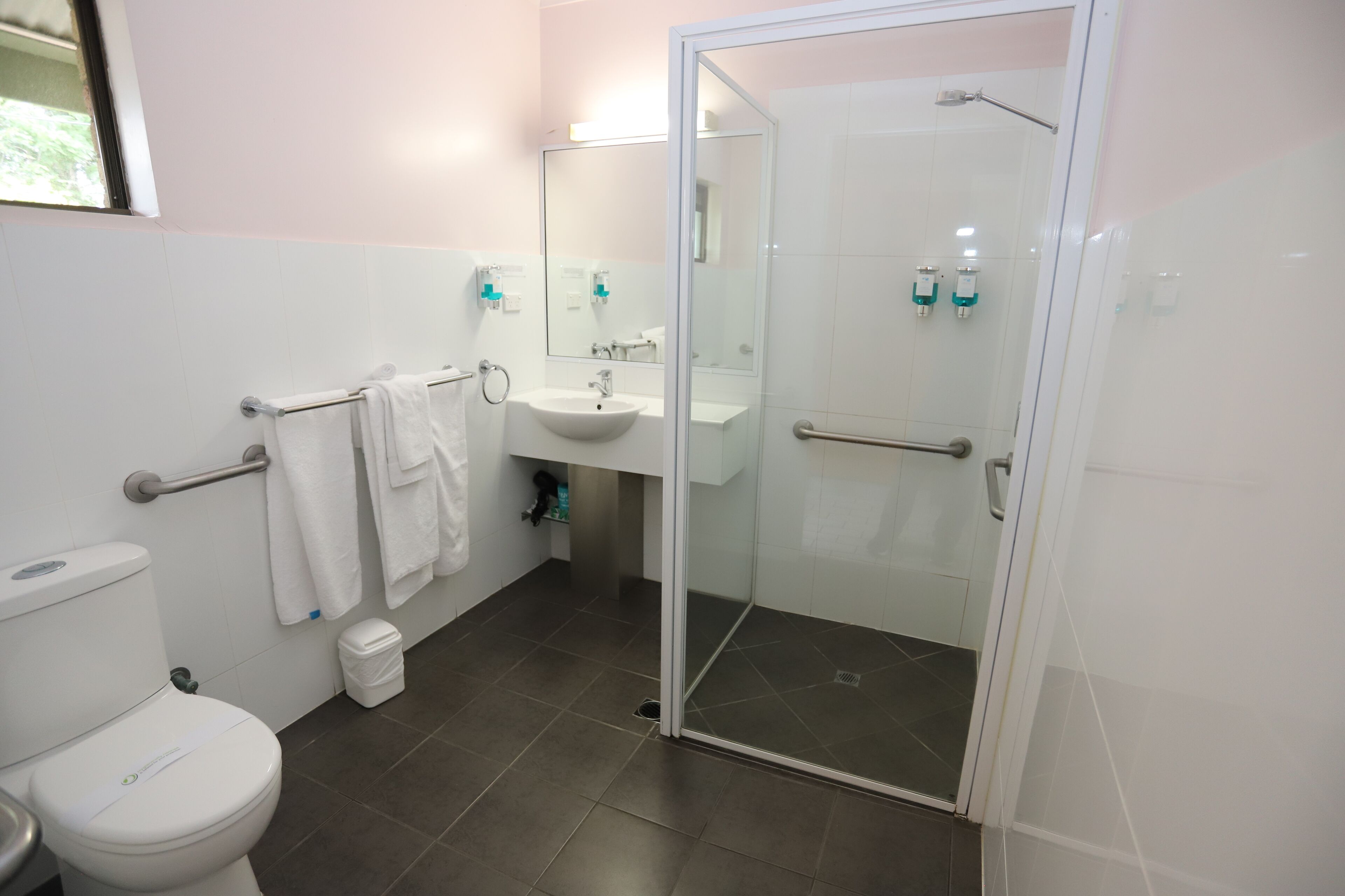 A modern bathroom with a toilet, sink, and glass-enclosed shower.