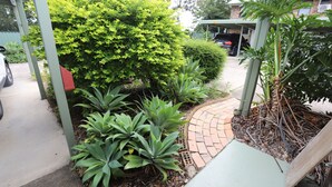 A garden with various plants and a brick pathway. - Great Eastern Motor Inn (Monkland)