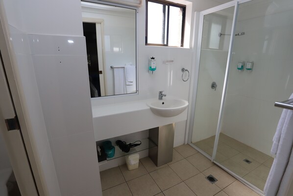 A modern bathroom with a glass shower enclosure, a white sink, and a mirror above it.