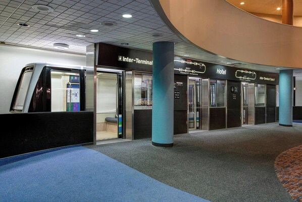 Una terminal de aeropuerto con un cartel de Interconexión, un anuncio de Hotel y un área de carrusel de equipaje.