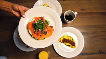 A wooden table with plates of food, a cup of coffee, and a lemon.