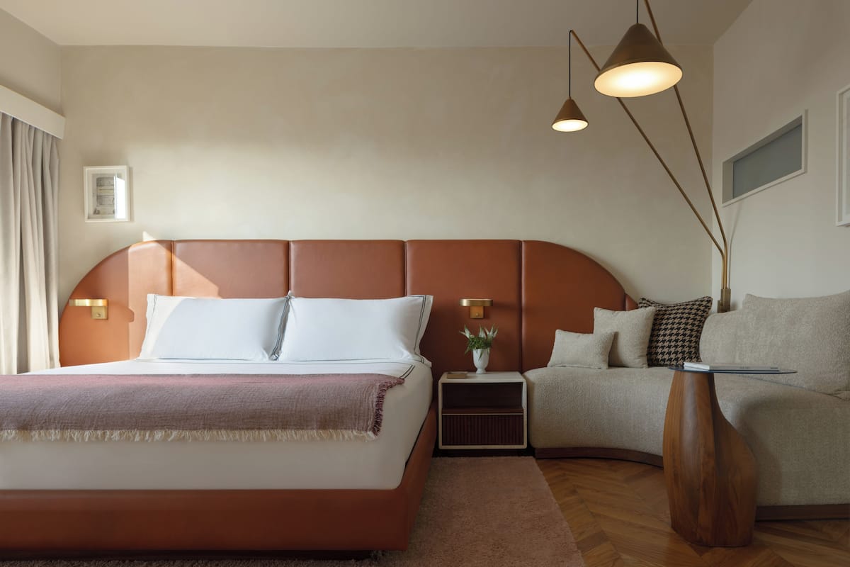 A modern bedroom with a large bed, a sofa, and a small table.