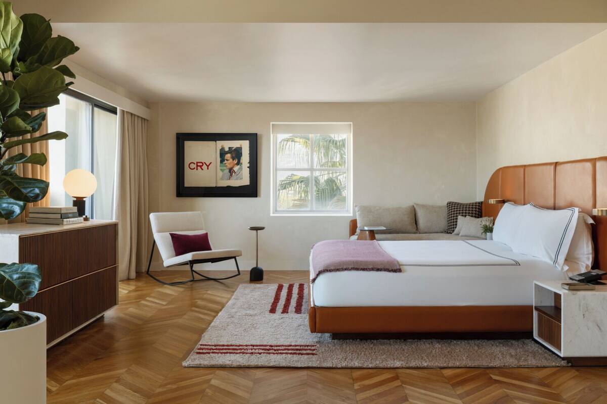 A bedroom with a bed, a chair, a desk, a lamp, a framed picture, and a window.