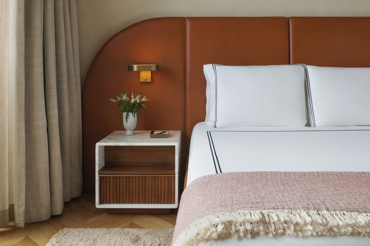 A neatly arranged bedroom with a bed, bedside table, and a small plant.
