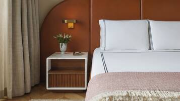 A neatly arranged bedroom with a bed, bedside table, and a small plant.