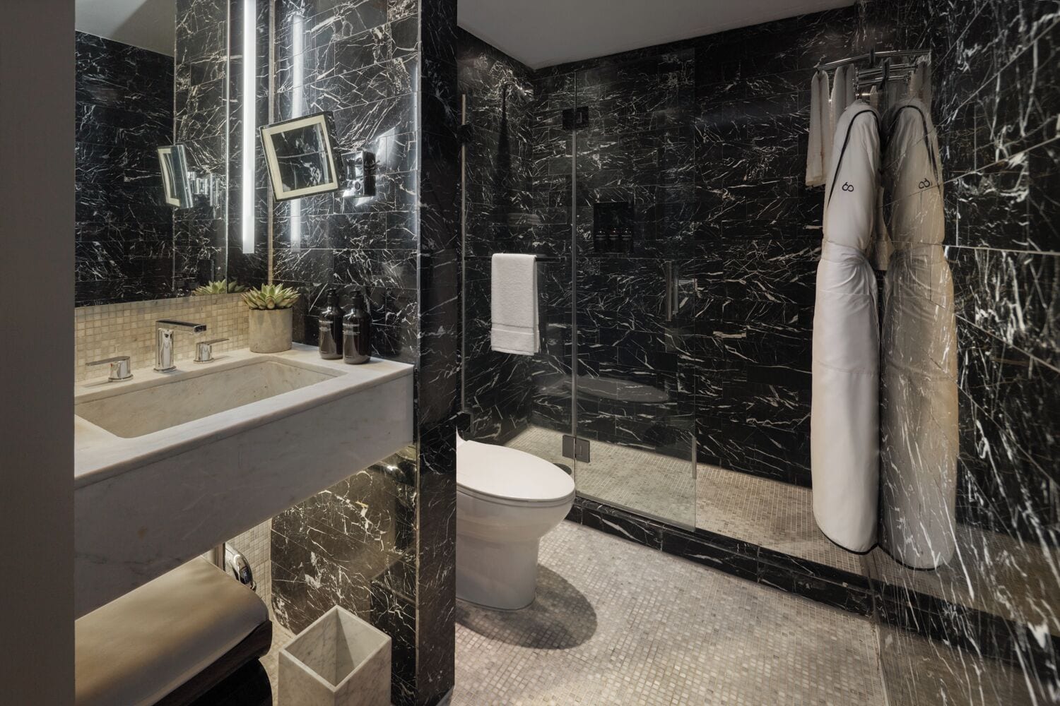 A modern bathroom with a marble sink, a toilet, and a shower area.