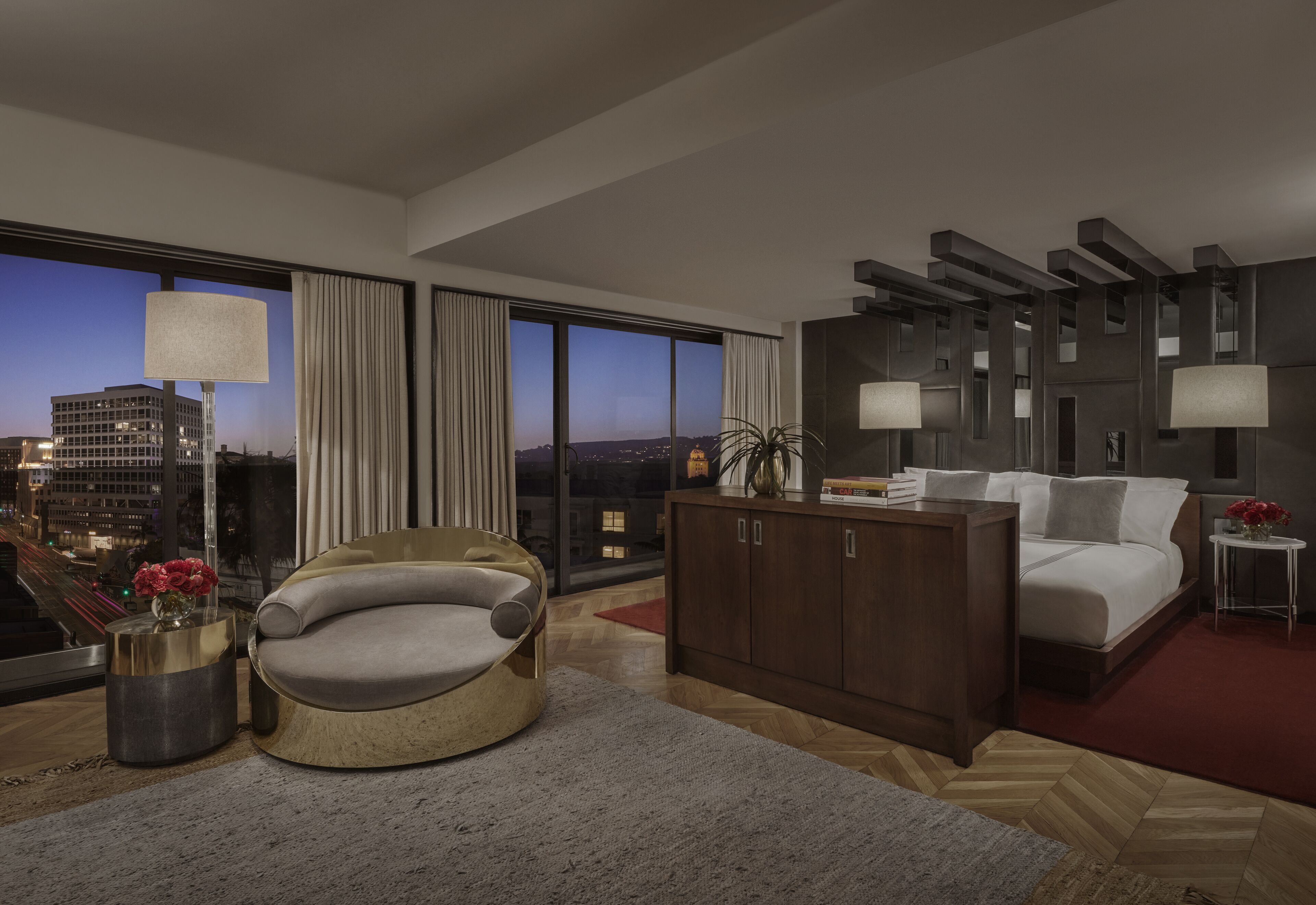 Quarto de hotel moderno com uma janela grande, uma cadeira redonda, uma cama e um armário de madeira.