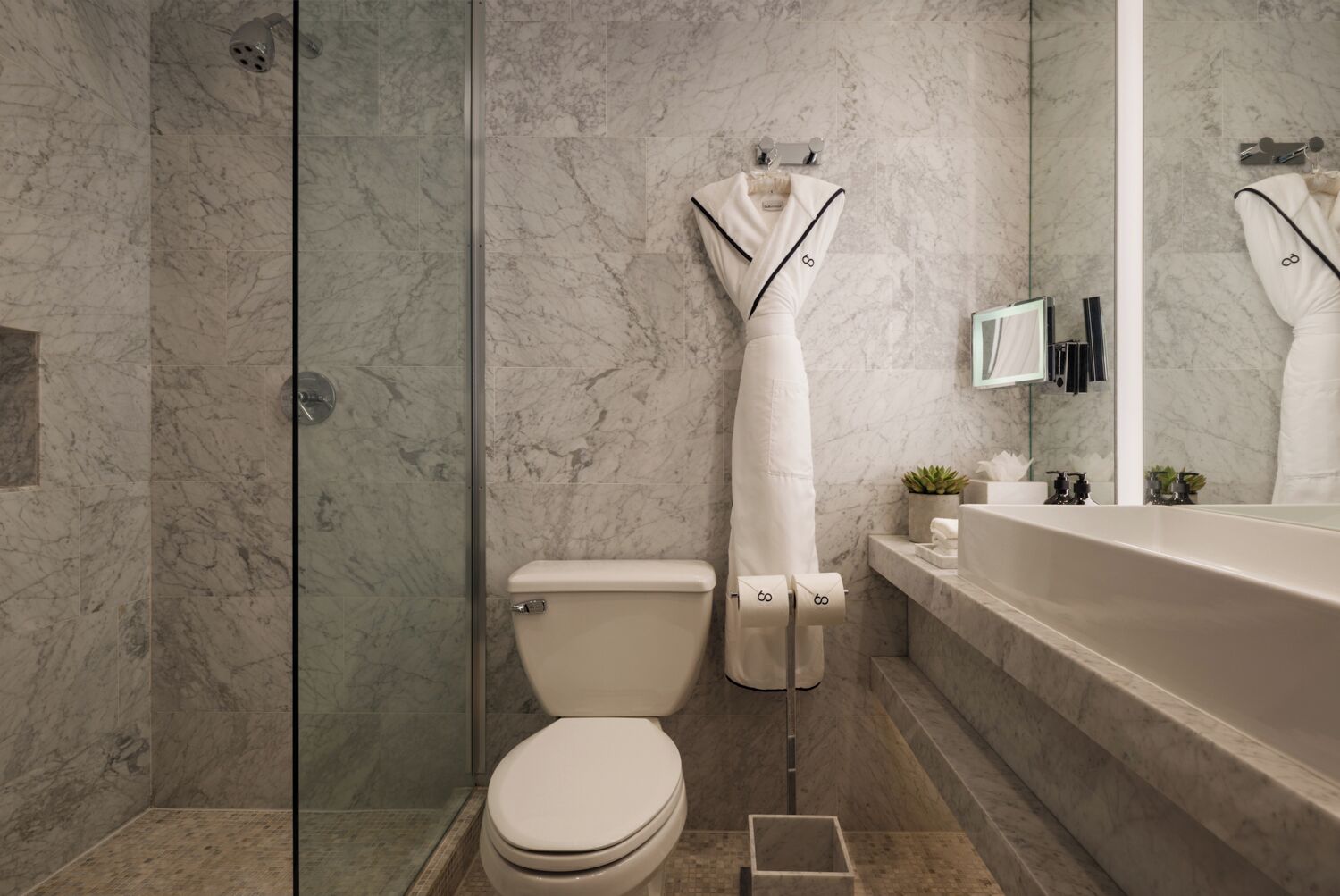 Un baño moderno con piso de mármol, ducha con cerramiento de vidrio, inodoro y bañera.