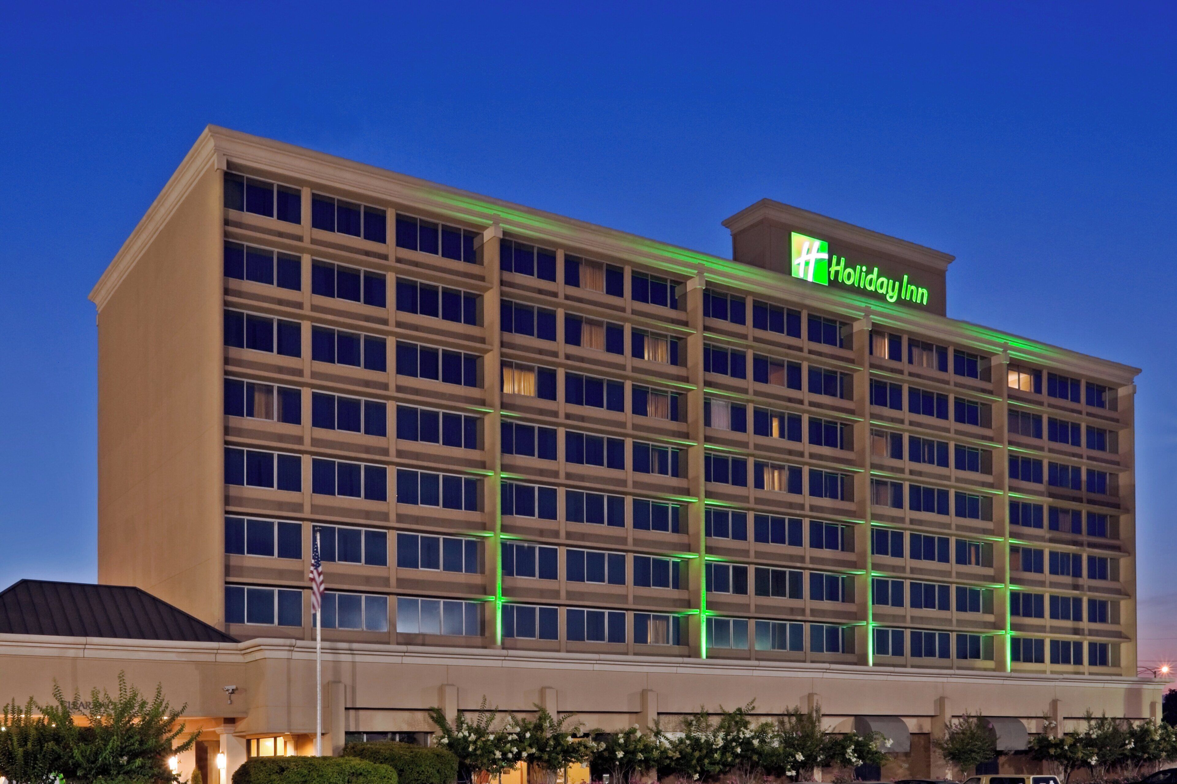 A Holiday Inn hotel with a large, multi-story building and a prominent green sign.