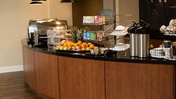 A buffet counter with a variety of food items, including fruits, cereals, and beverages.