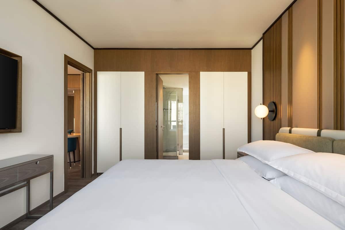 Una habitación de hotel moderna con una cama grande, un escritorio y un televisor en la pared.