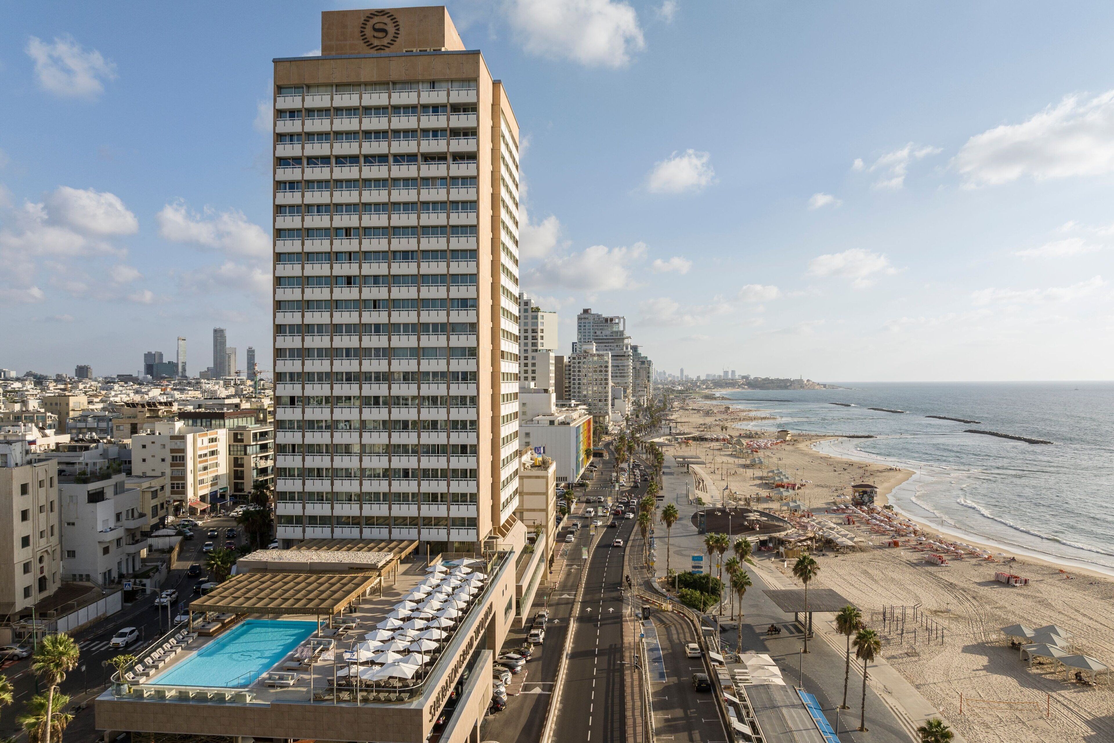 A high-rise hotel with a rooftop pool, beachfront location, and a view of the ocean.