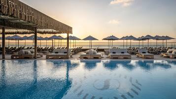 Alberca al aire libre, sombrillas en la alberca y camastros