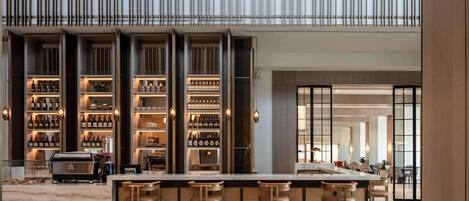 A modern bar area with a marble countertop, bar stools, and a wine display.
