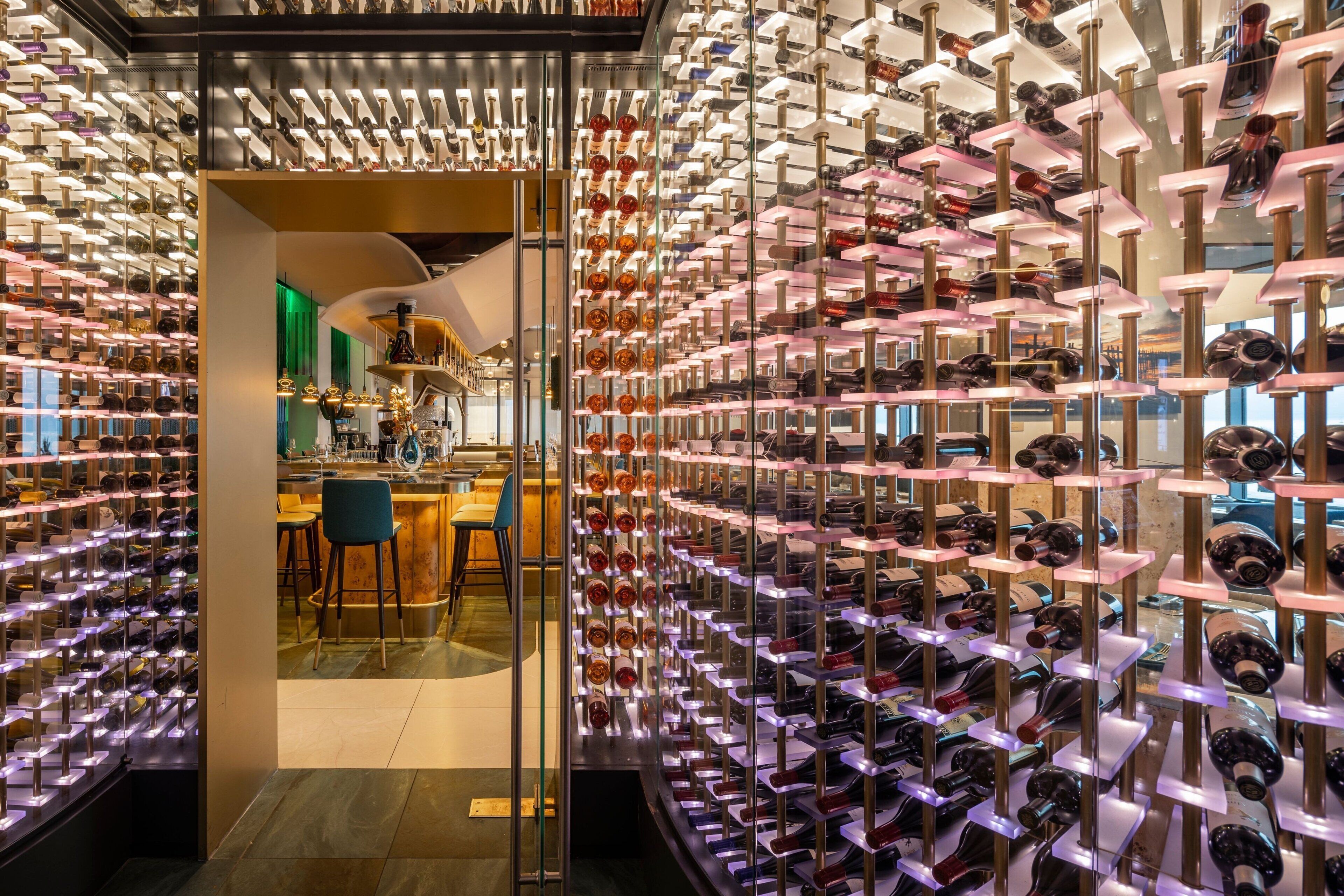 Un hall d’hôtel de luxe doté d’une cave à vin, avec des rangées de bouteilles de vin et un espace bar.