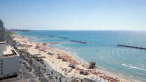 A beach with umbrellas, a pier, and a city skyline in the background. - Sheraton Grand Tel Aviv (Tel Aviv)